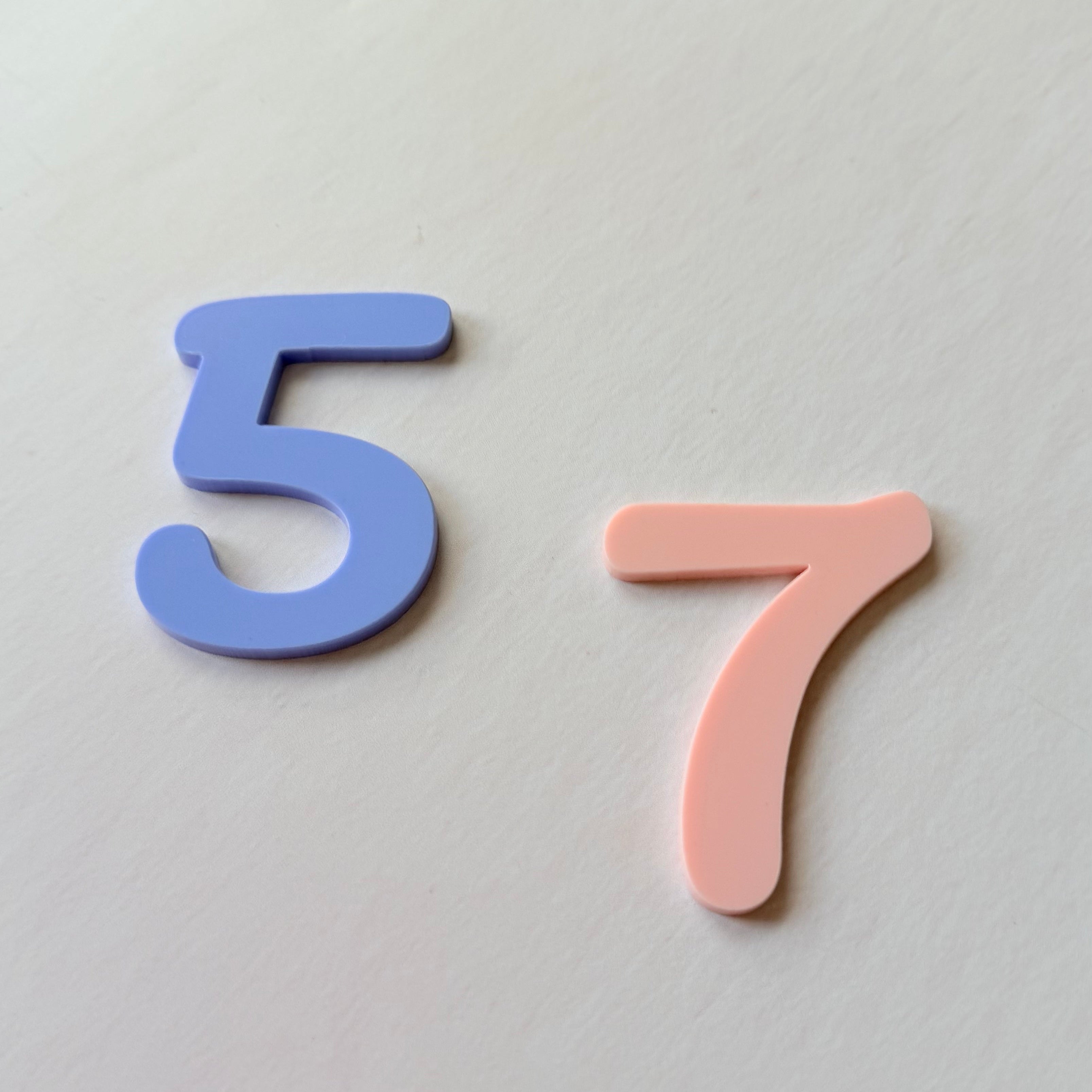 Blue and pink numbers '5' and '7' on a light gray background