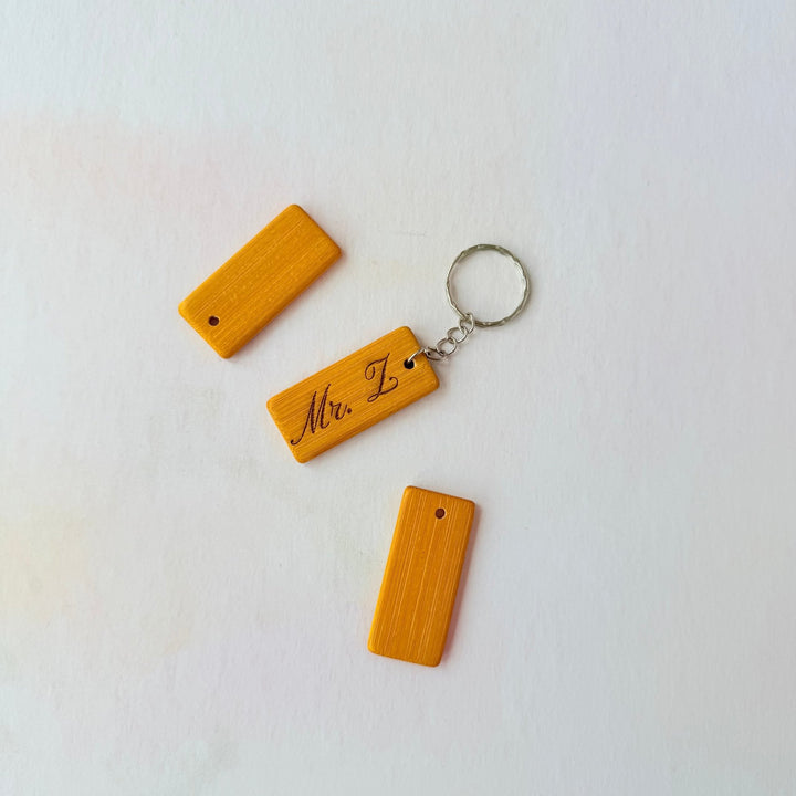 Three amber bamboo keyrings, one engraved with custom text on a silver ring – personalised bamboo keyring – Etch 'N' Shine