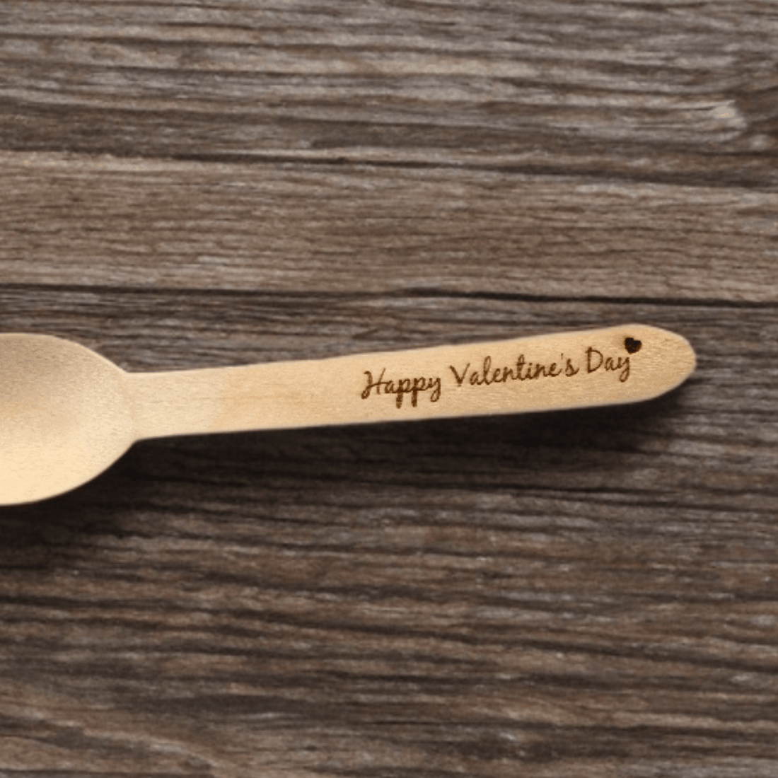 Laser-engraved wooden spoon handle with personalised message on a wood surface – engraved wooden spoon – Etch 'N' Shine