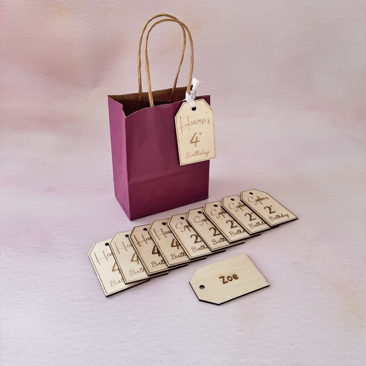 Purple gift bag with personalized tags on a light background