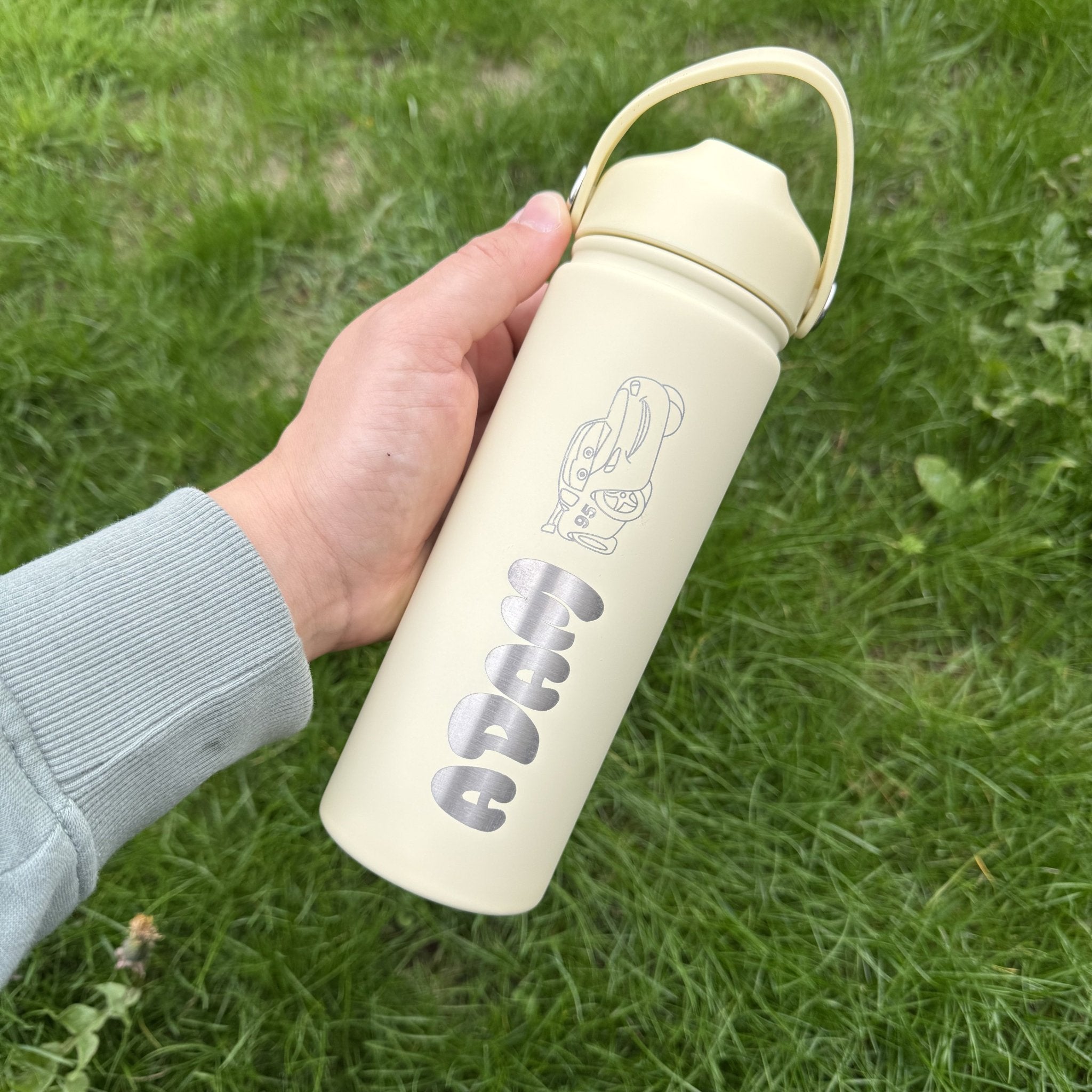 Cream insulated bottle with custom name held outdoors – personalised steel water bottle – Etch 'N' Shine