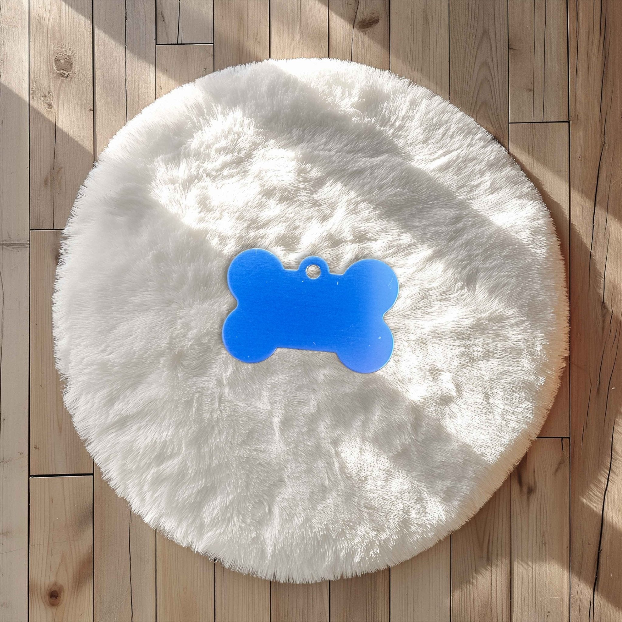 Blue bone-shaped pet tag on a white fluffy rug – personalised engraved metal dog tag – Etch 'N' Shine