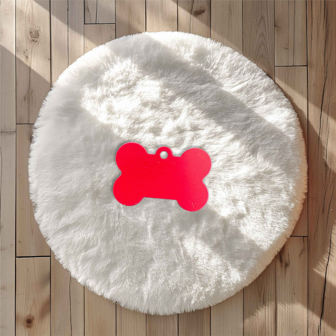 Red bone-shaped pet tag on a white fluffy rug – personalised engraved metal pet name tag – Etch 'N' Shine