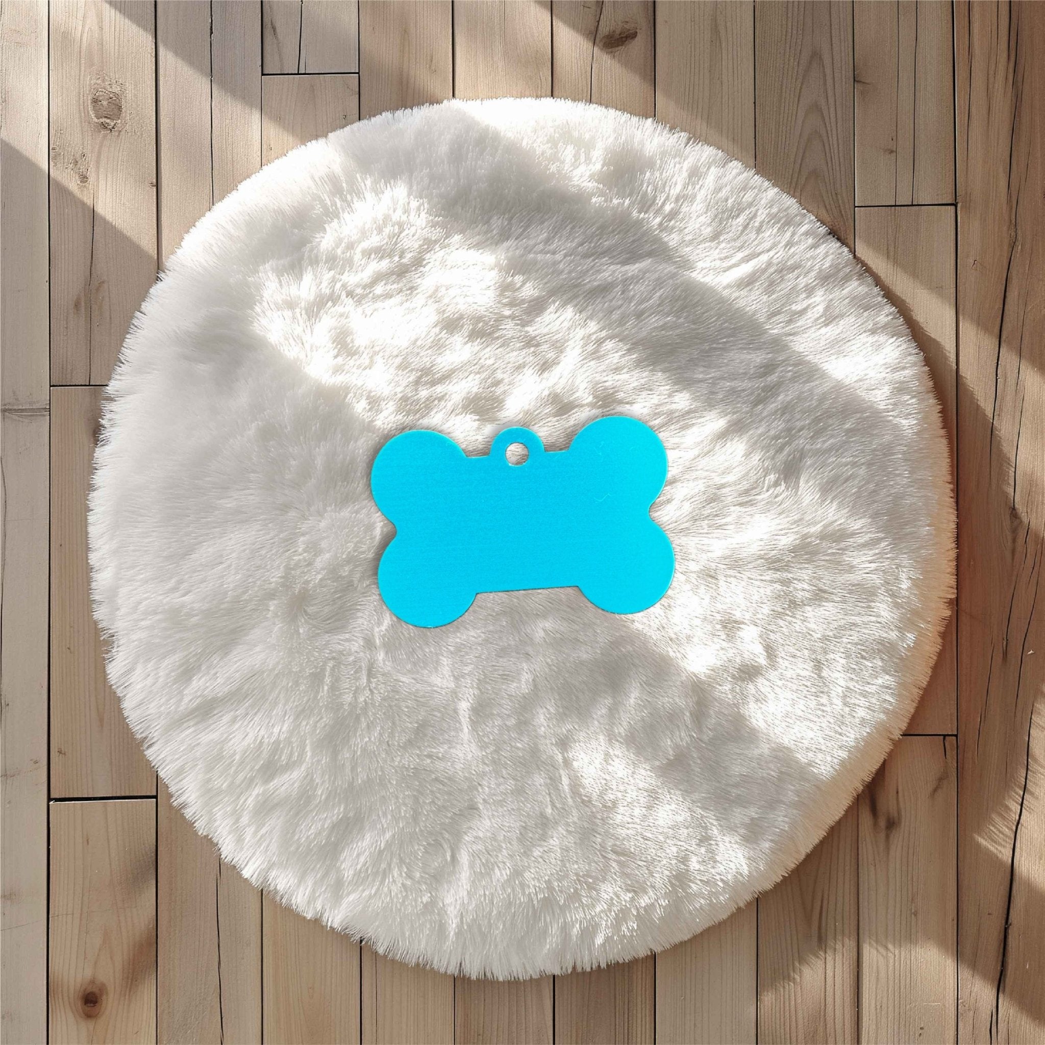 Blue bone-shaped pet tag on a white fluffy rug – personalised engraved metal pet name tag – Etch 'N' Shine