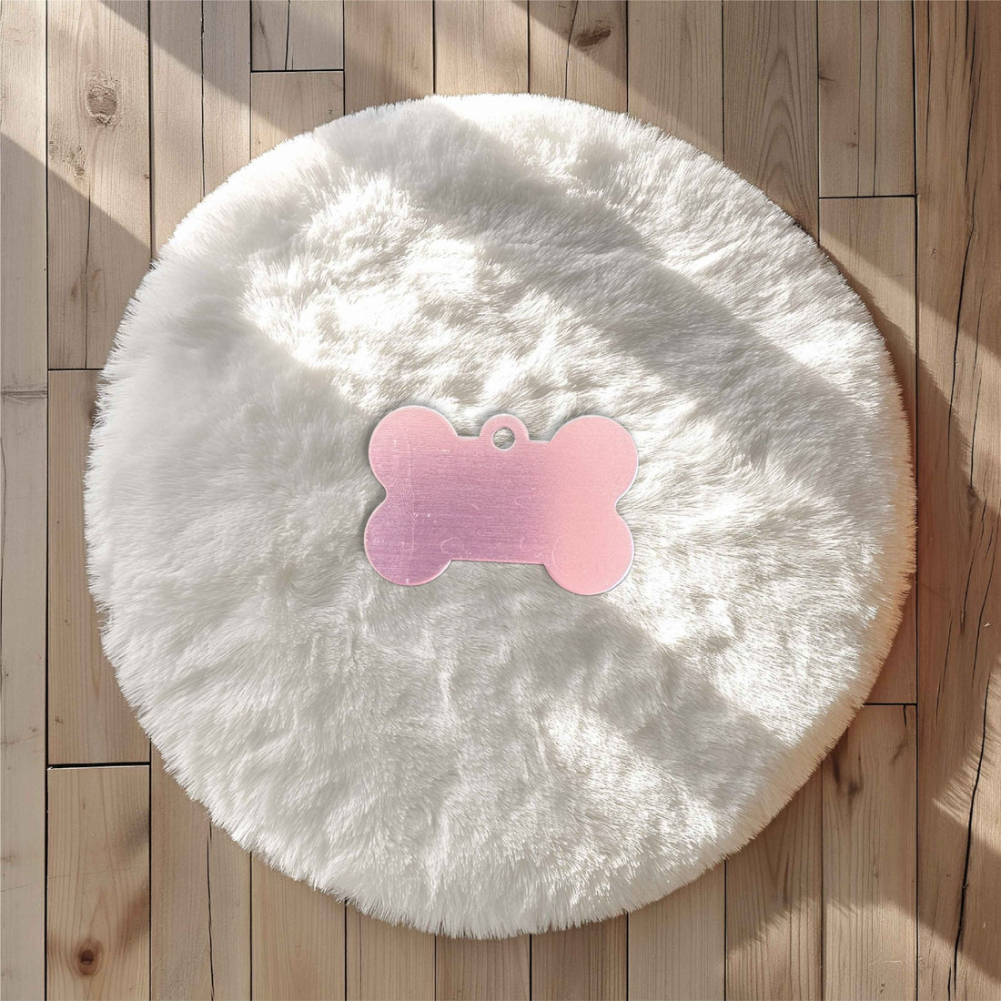 Pink bone-shaped pet tag on a white fluffy surface – personalised aluminium pet name tag – Etch 'N' Shine