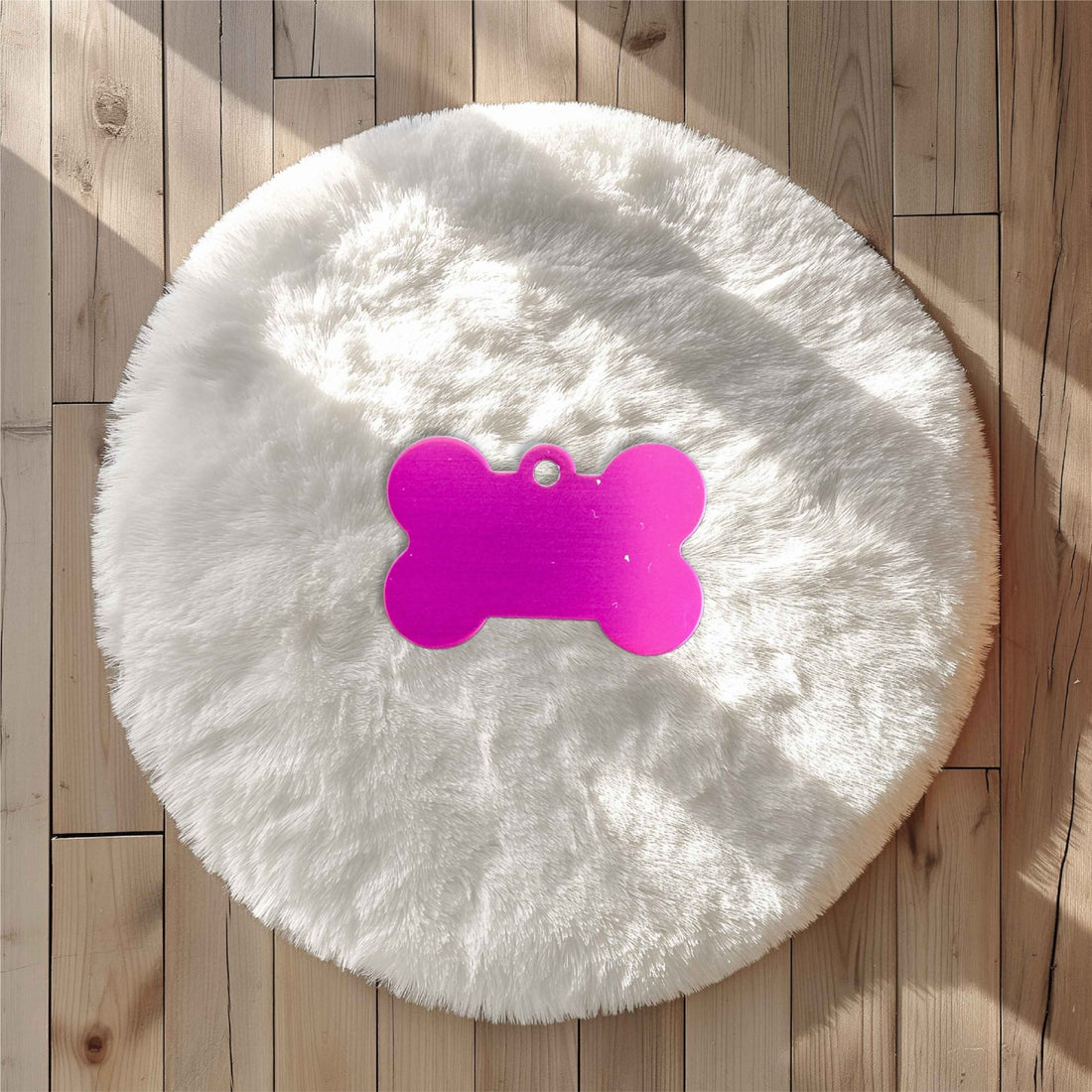 Pink bone-shaped pet tag on a white fluffy rug – personalised engraved metal pet name tag – Etch 'N' Shine