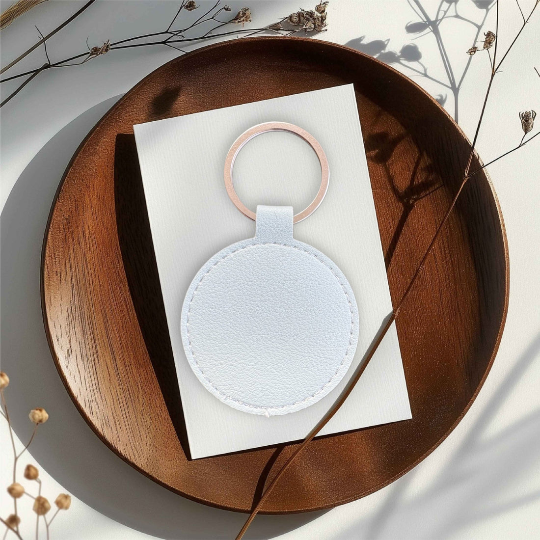 Round white leather keyring with rose gold ring on a wooden tray – personalised engraved PU leather keyring – Etch 'N' Shine