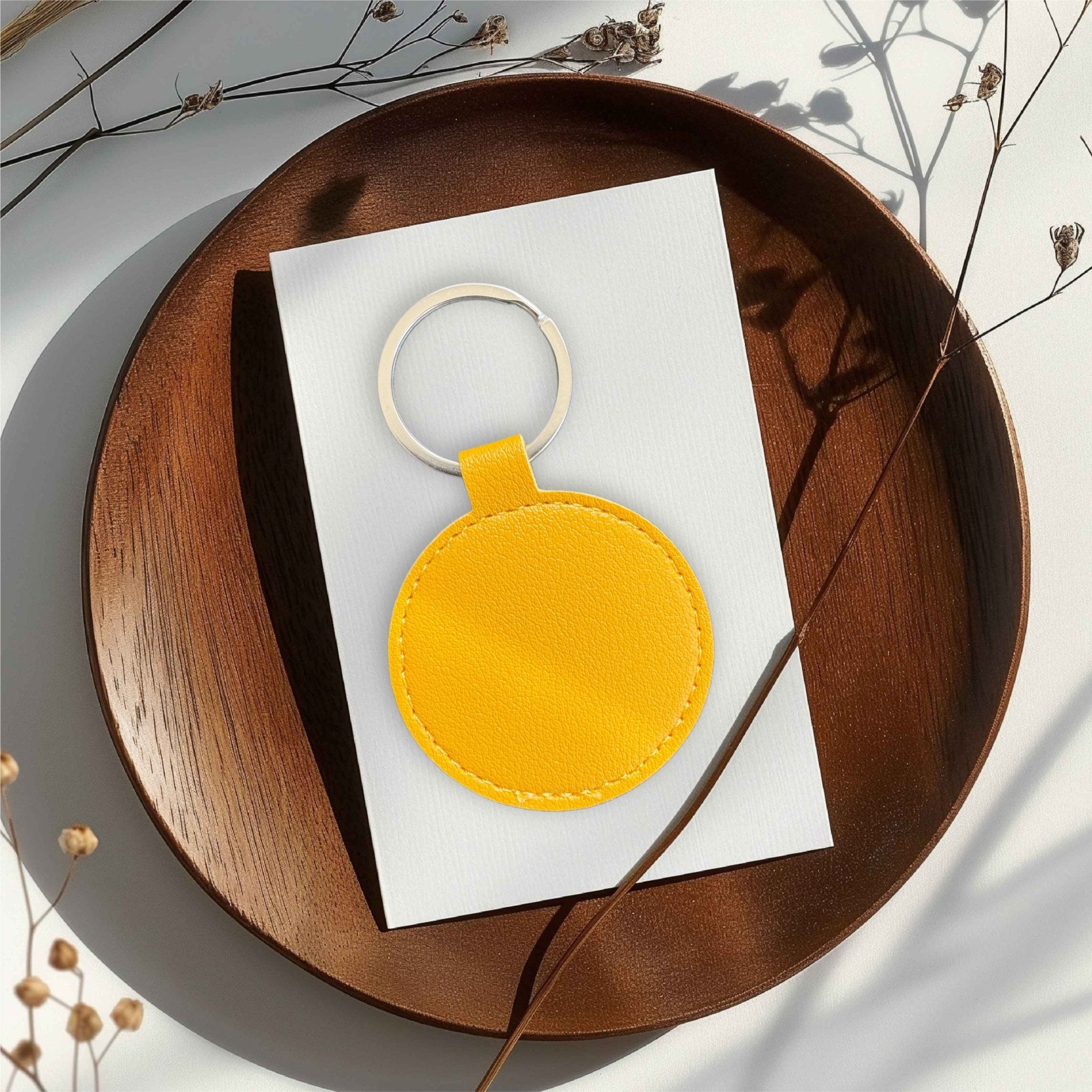 Round yellow leather keyring on a white card atop a wooden tray – personalised PU leather keyring – Etch 'N' Shine