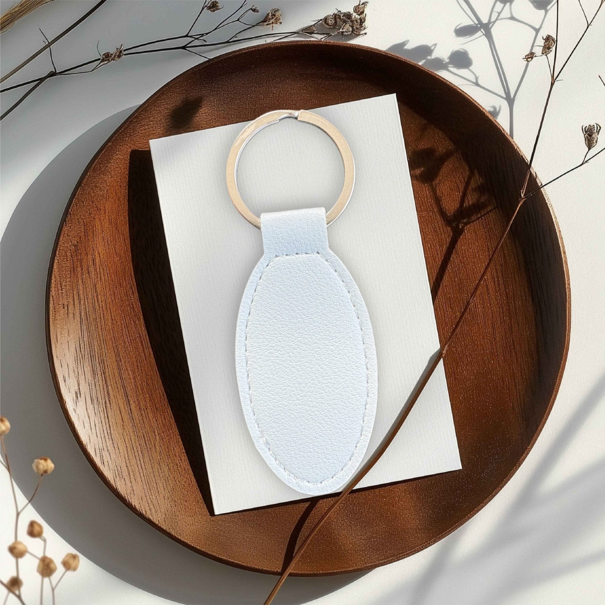 Oval white PU leather keyring on a wooden tray – personalised engraved leather keyring – Etch 'N' Shine