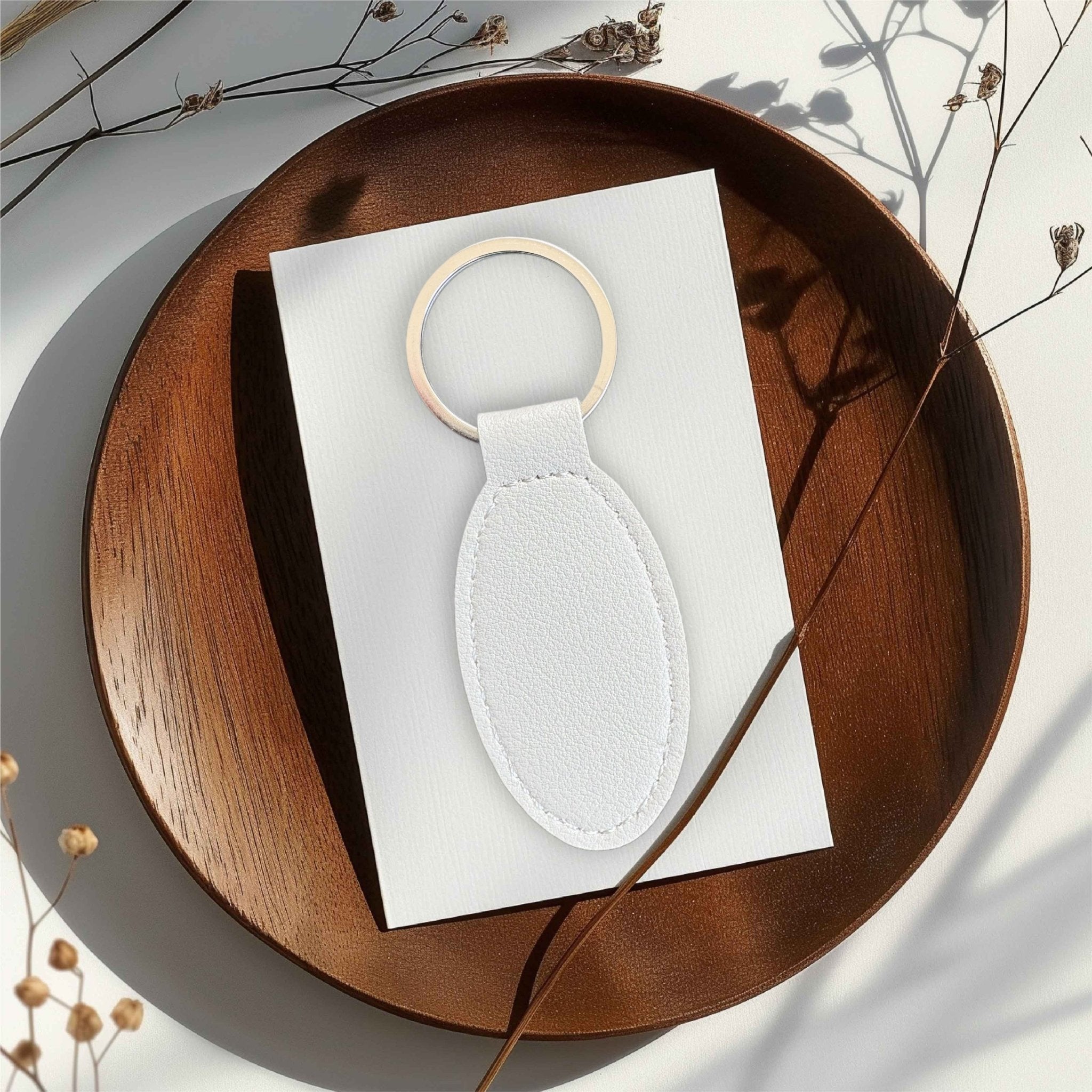 White oval leather keyring with silver ring on a wooden tray – personalised engraved PU leather keyring – Etch 'N' Shine