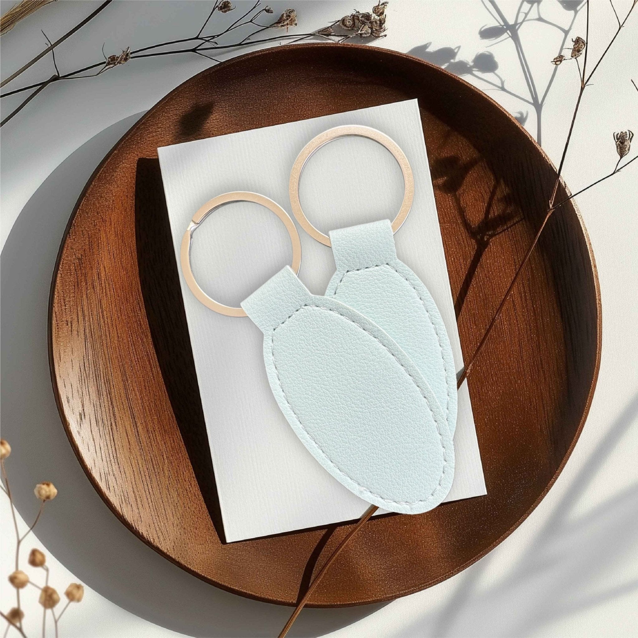 Two pale blue oval keyrings on a wooden tray – personalised engraved leather keyring – Etch 'N' Shine