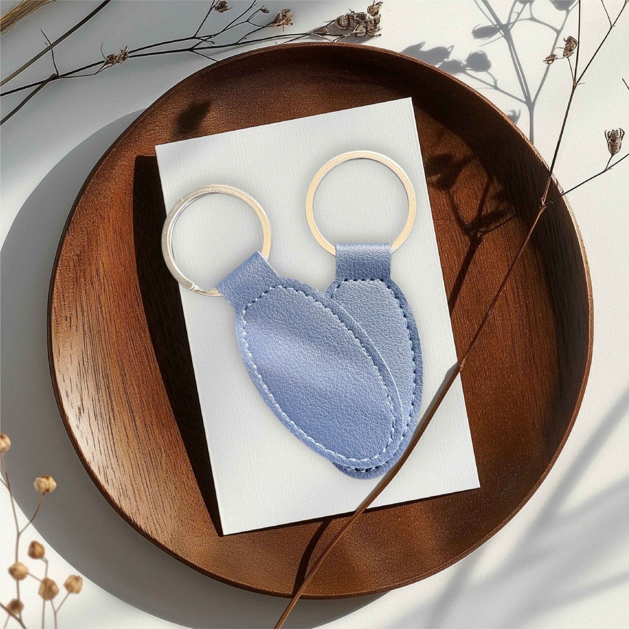 Two blue oval PU leather keyrings on a wooden tray – personalised engraved leather keyring – Etch 'N' Shine