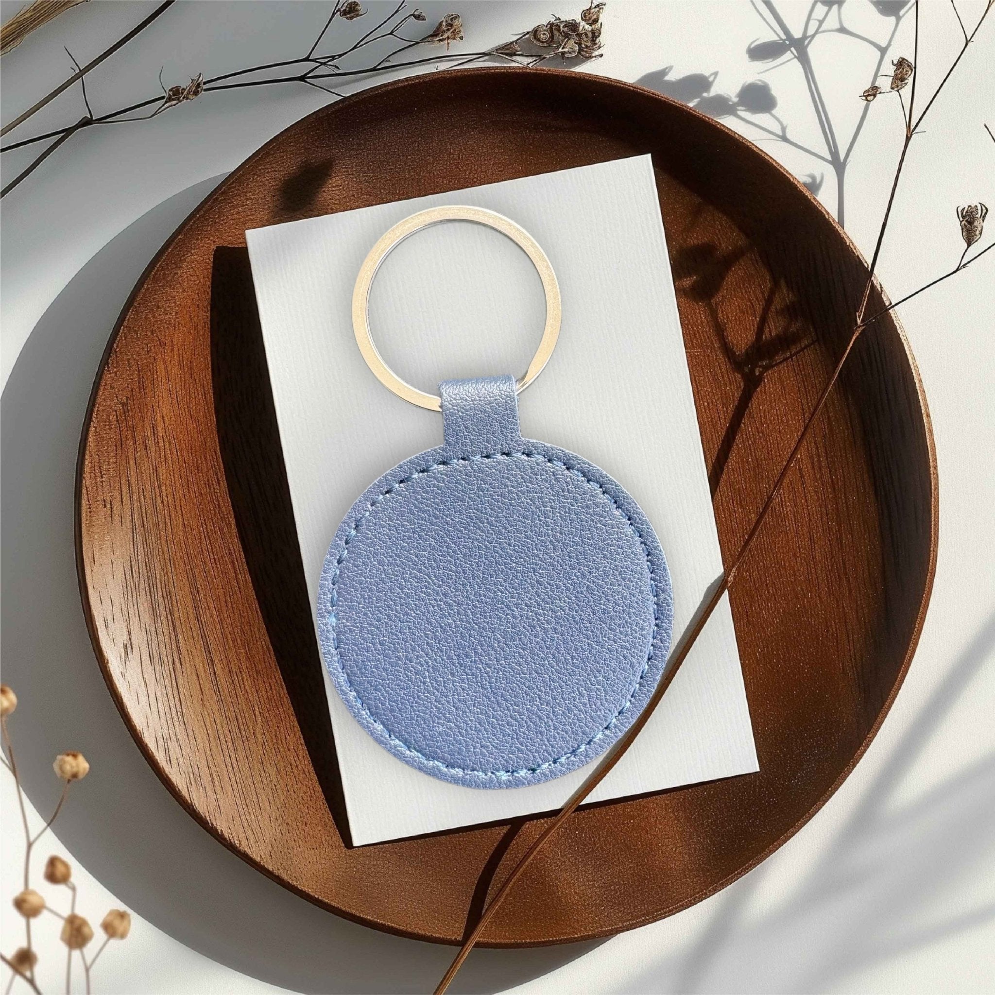 Round blue PU leather keyring with gold ring on a wooden tray – personalised engraved leather keyring – Etch 'N' Shine