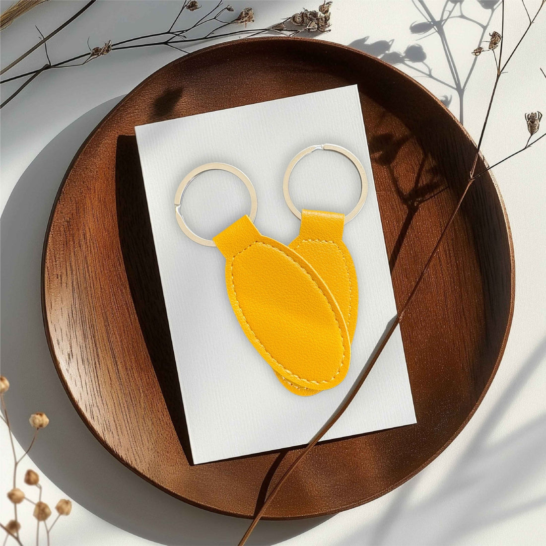 Two yellow oval leather keyrings on a wooden tray – personalised engraved PU leather keyring – Etch 'N' Shine