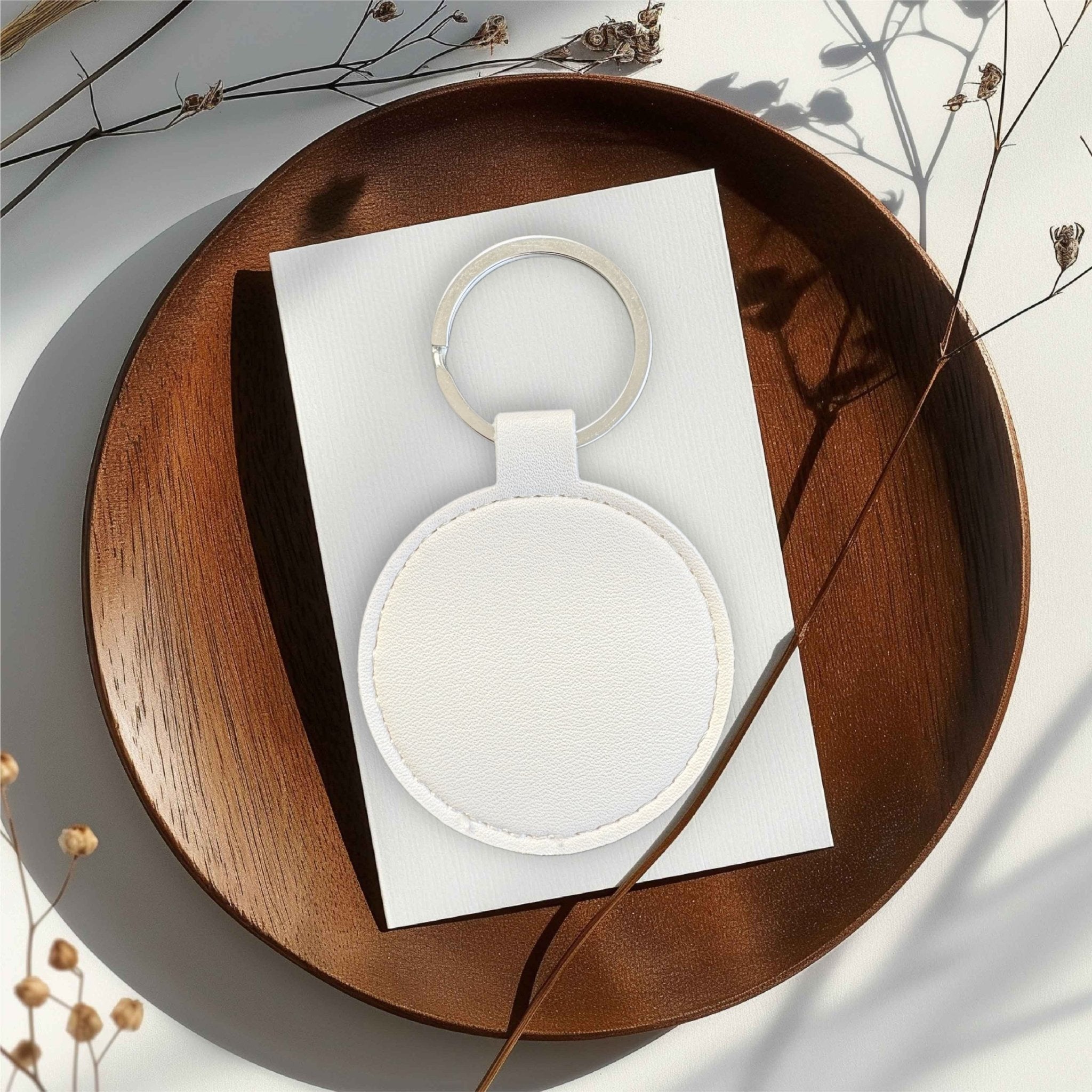 Round white leather keyring on a card on a wooden tray – personalised engraved PU leather keyring – Etch 'N' Shine