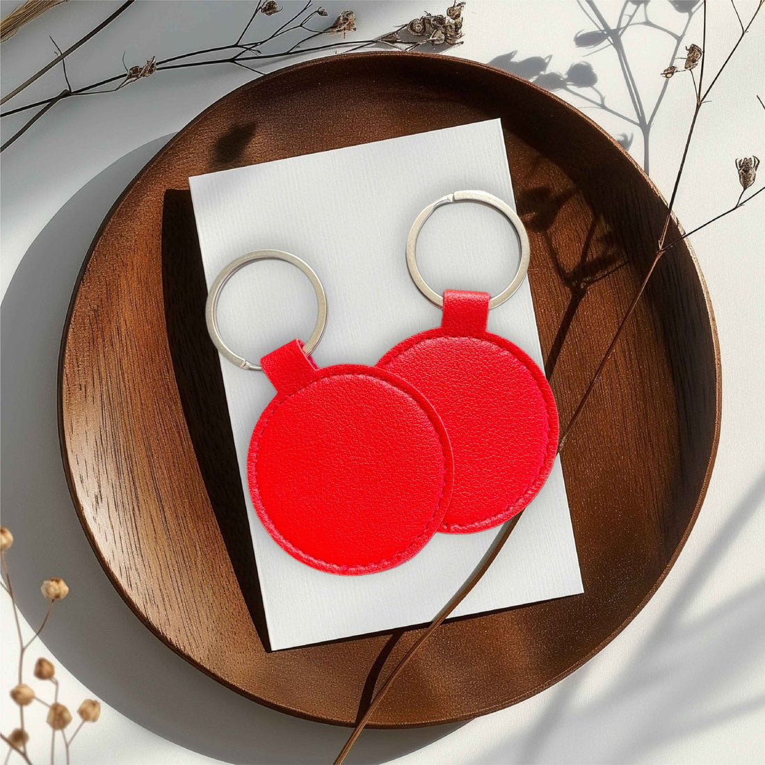 Two red round keyrings on a wooden tray – personalised PU leather keyring – Etch 'N' Shine
