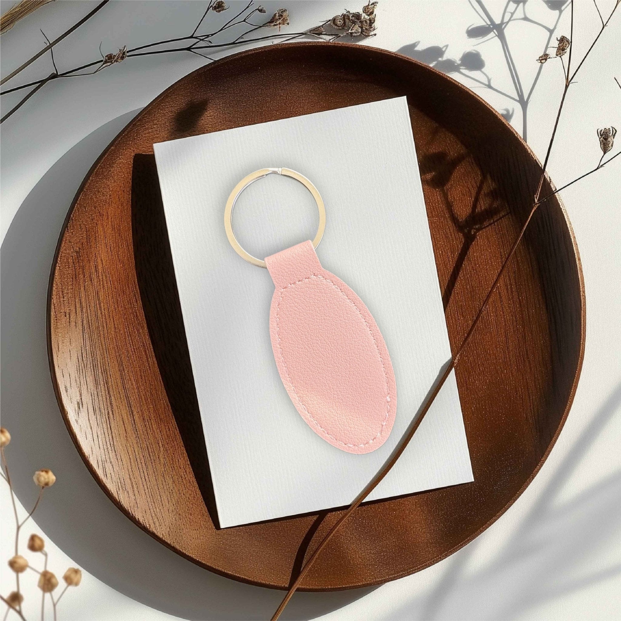 Pink oval leather keyring on a white card atop a wooden tray – personalised engraved PU leather keyring – Etch 'N' Shine