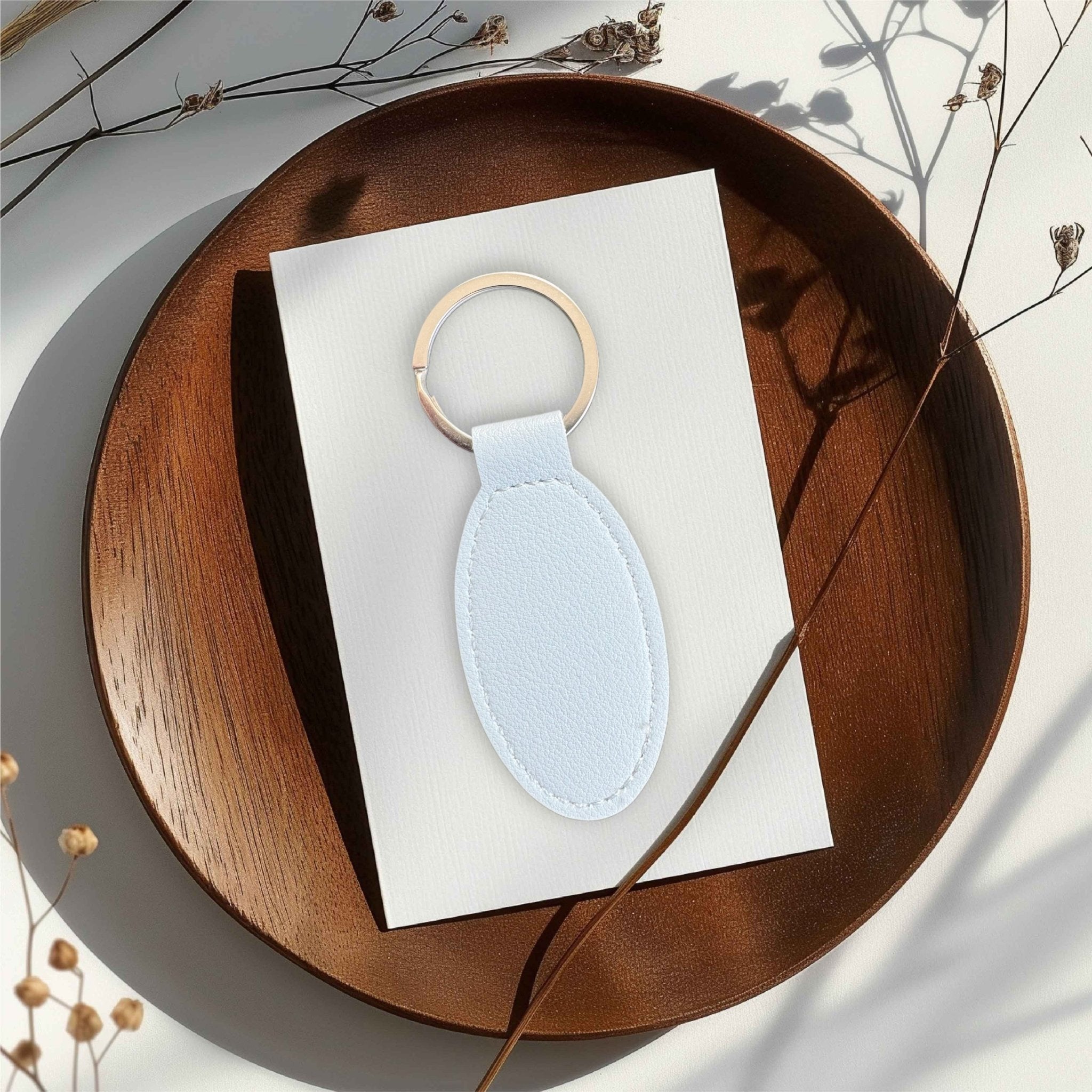 Pale blue oval keyring on a white card atop a wooden tray – personalised engraved PU leather keyring – Etch 'N' Shine