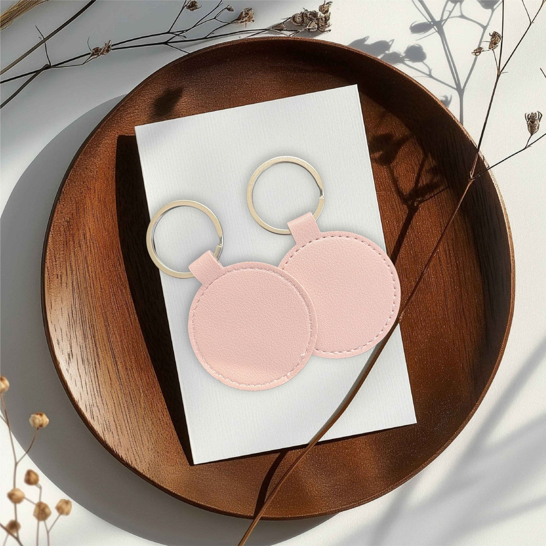 Two round pink leather keyrings on a white card atop a wooden tray – personalised PU leather keyring – Etch 'N' Shine