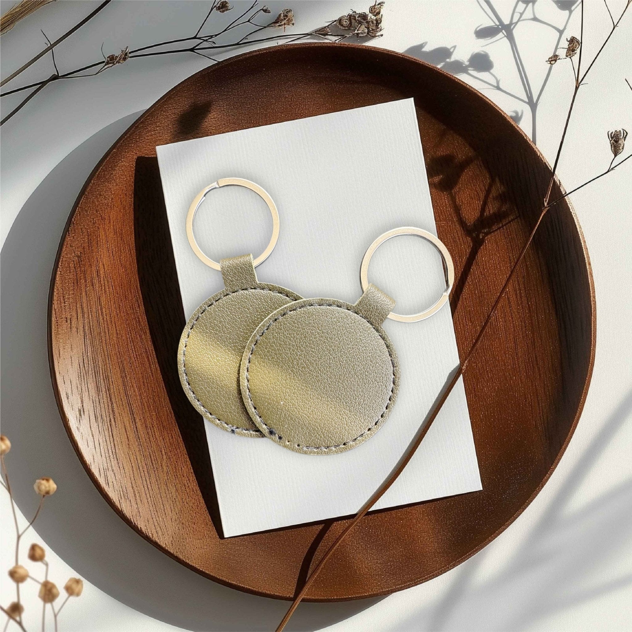Two gold round keyrings on a white card atop a wooden tray – personalised engraved PU leather keyring – Etch 'N' Shine