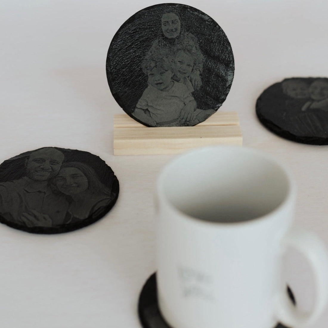 Round slate coasters with engraved photo portrait, shown with a mug – personalised slate coaster – Etch 'N' Shine