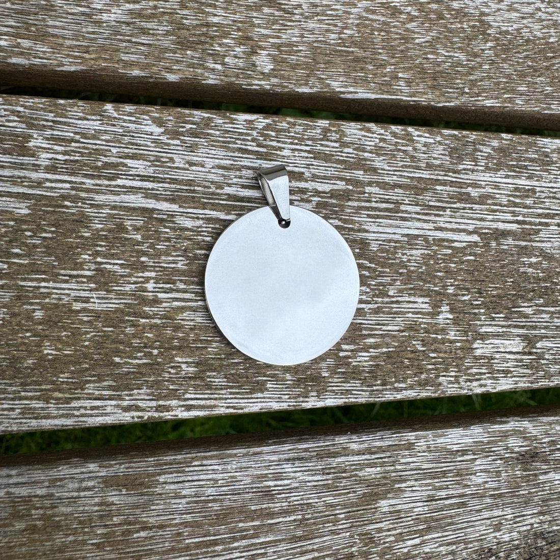 Round mirror-polished pendant on a weathered wooden surface – personalised stainless steel pendant – Etch 'N' Shine