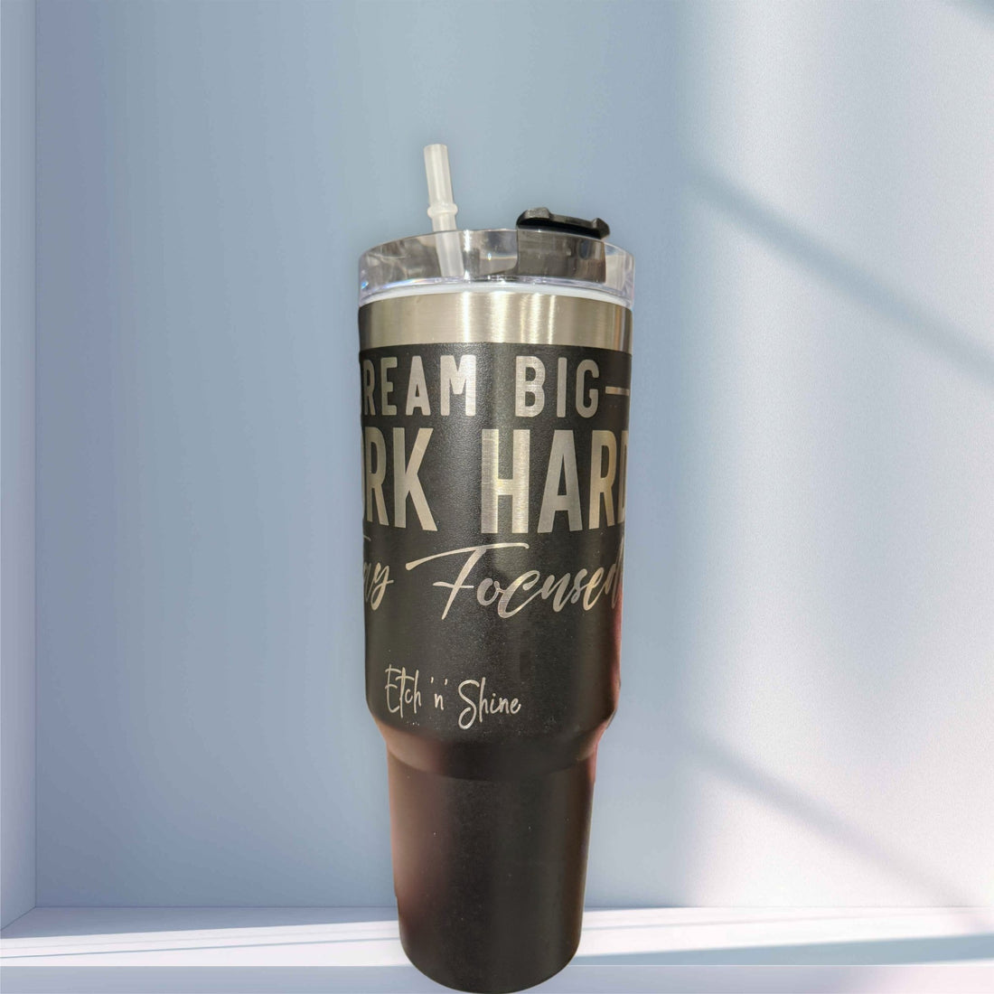 Dark engraved stainless steel tumbler with custom text and straw lid on a shelf – personalised steel tumbler – Etch 'N' Shine