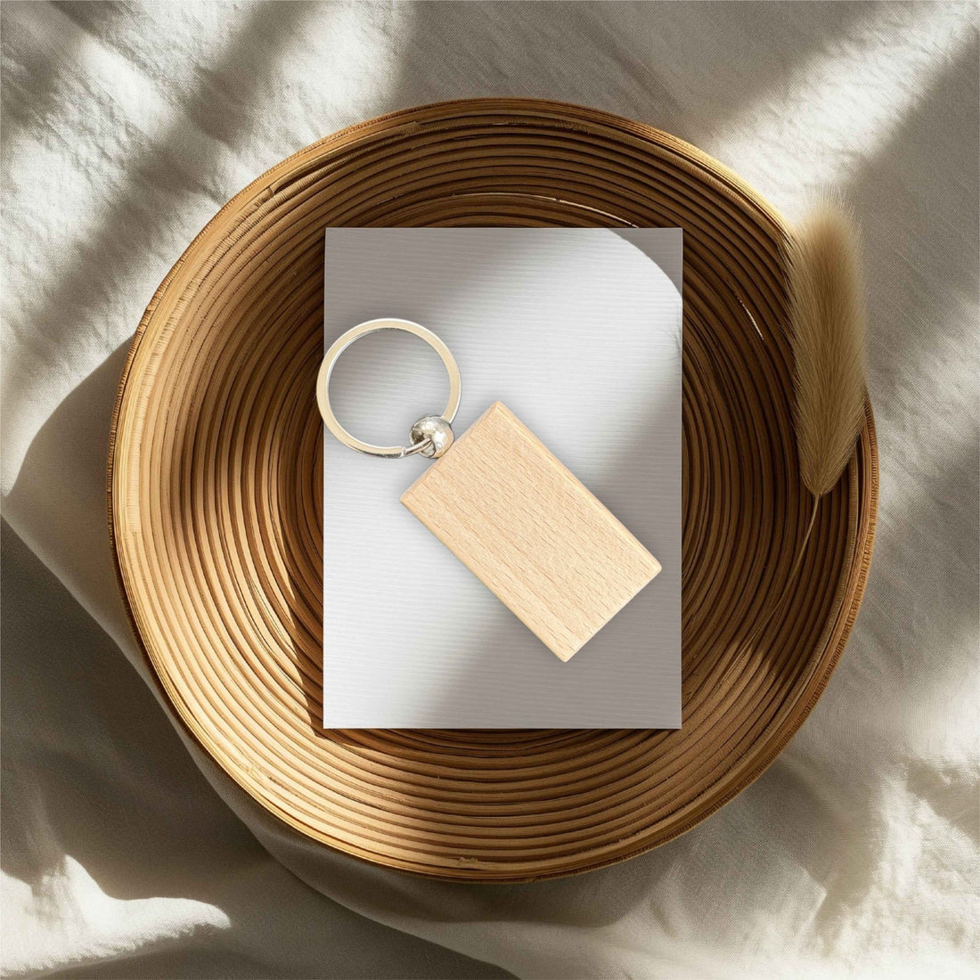 Rectangular wooden keyring with silver split ring on a card in a rattan tray – personalised wooden keyring – Etch 'N' Shine