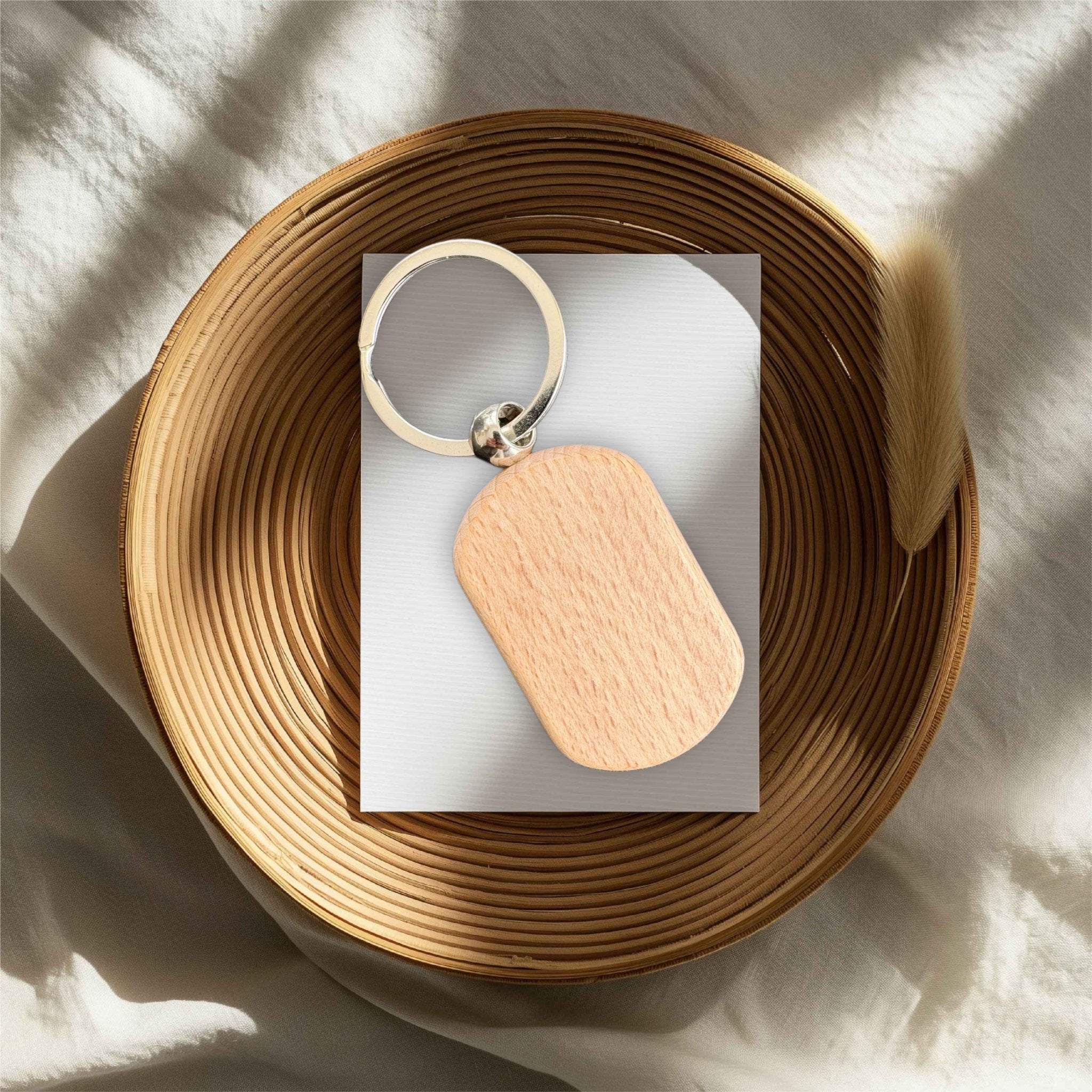 Rounded wooden keyring with silver split ring resting in a wicker bowl – personalised wooden keyring – Etch 'N' Shine