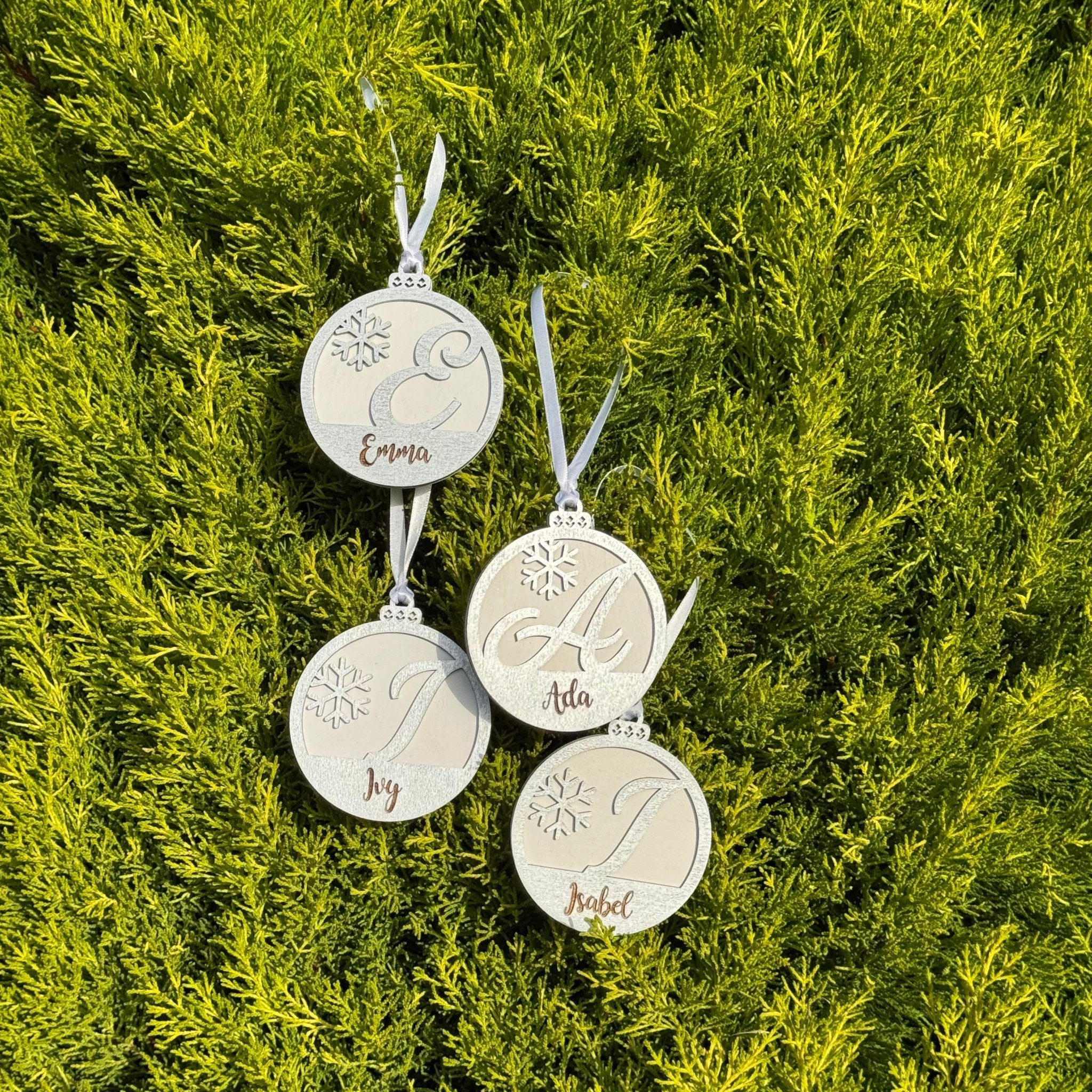 Four engraved wooden baubles with custom names on foliage – personalised Christmas ornaments – Etch 'N' Shine