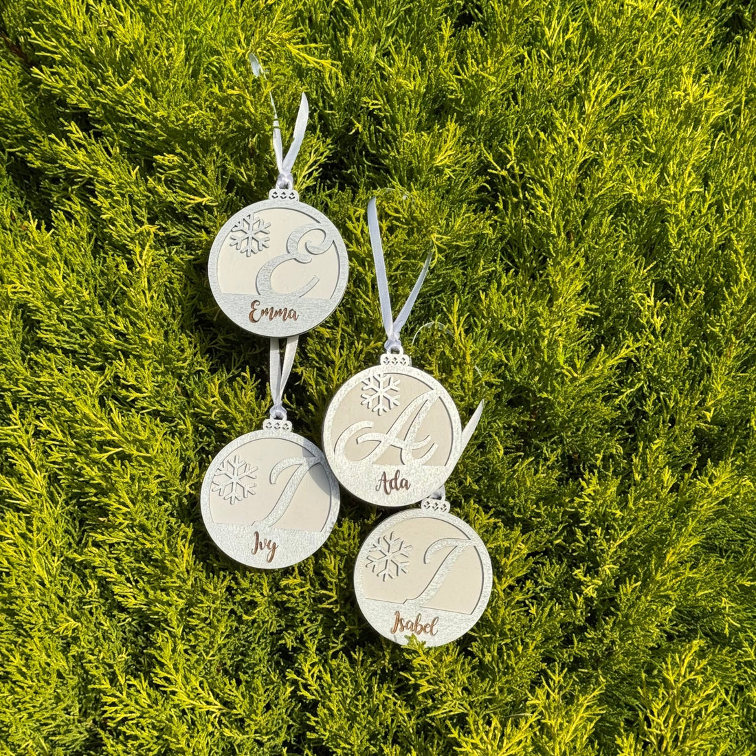 Four engraved wooden baubles with custom names on foliage – personalised Christmas ornaments – Etch 'N' Shine