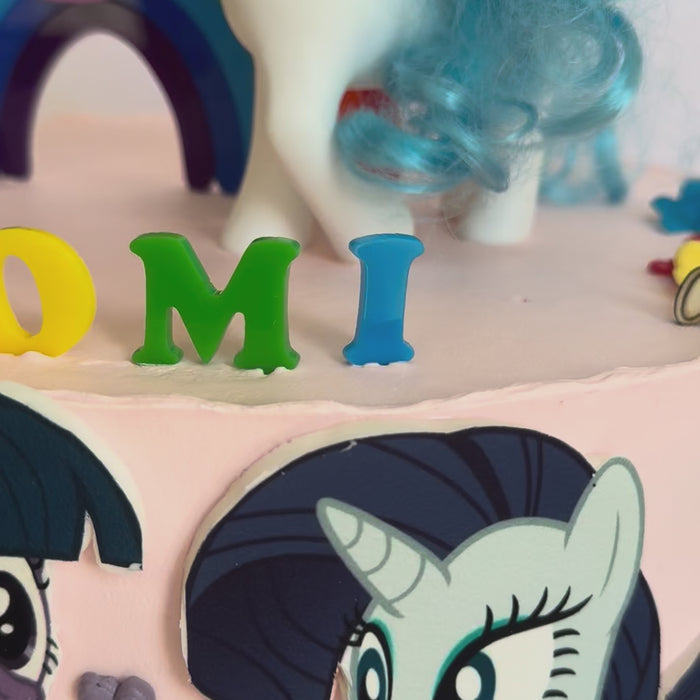 Video of the rainbow arch and NAOMI topper set on a cake, second view – Etch 'N' Shine
