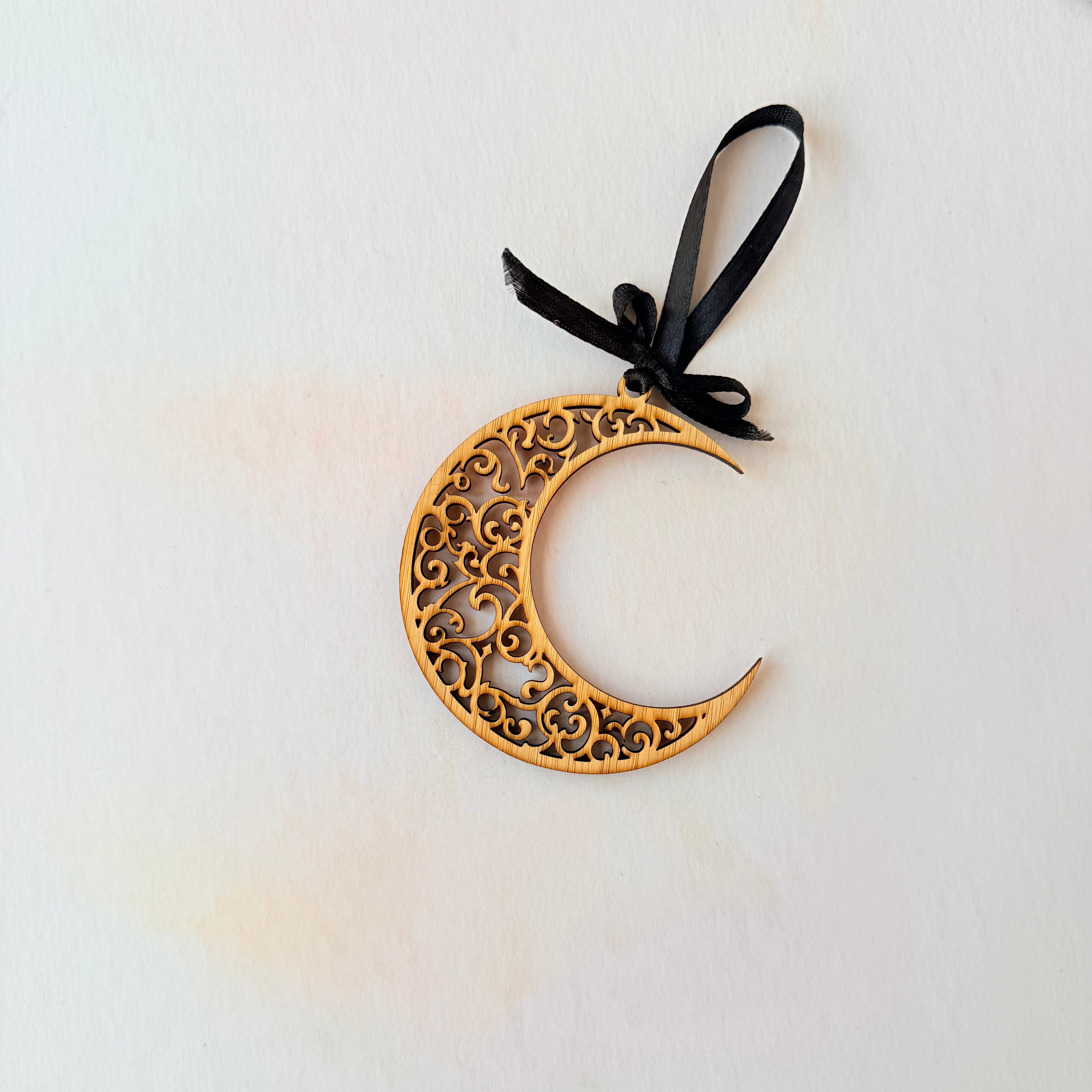 Decorative crescent moon ornament with intricate patterns on a white background