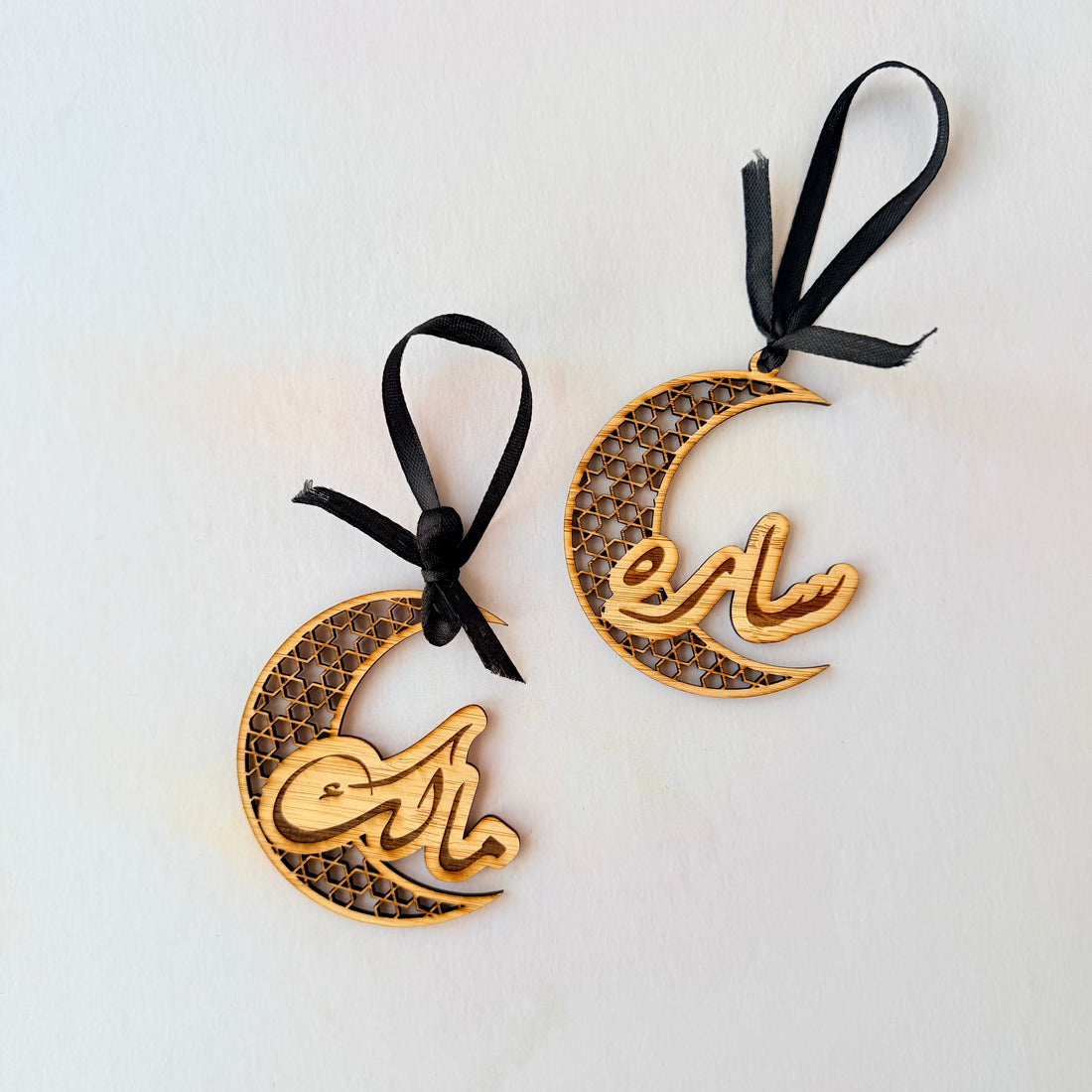 Two bamboo crescent moon-shaped decorations with 'Eid' text on a white background