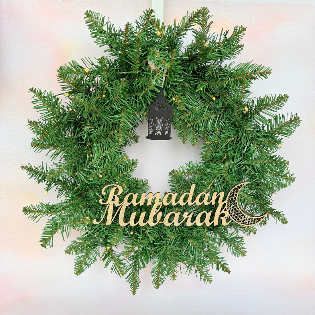 Green wreath with 'Ramadan Mubarak' decoration on a light background