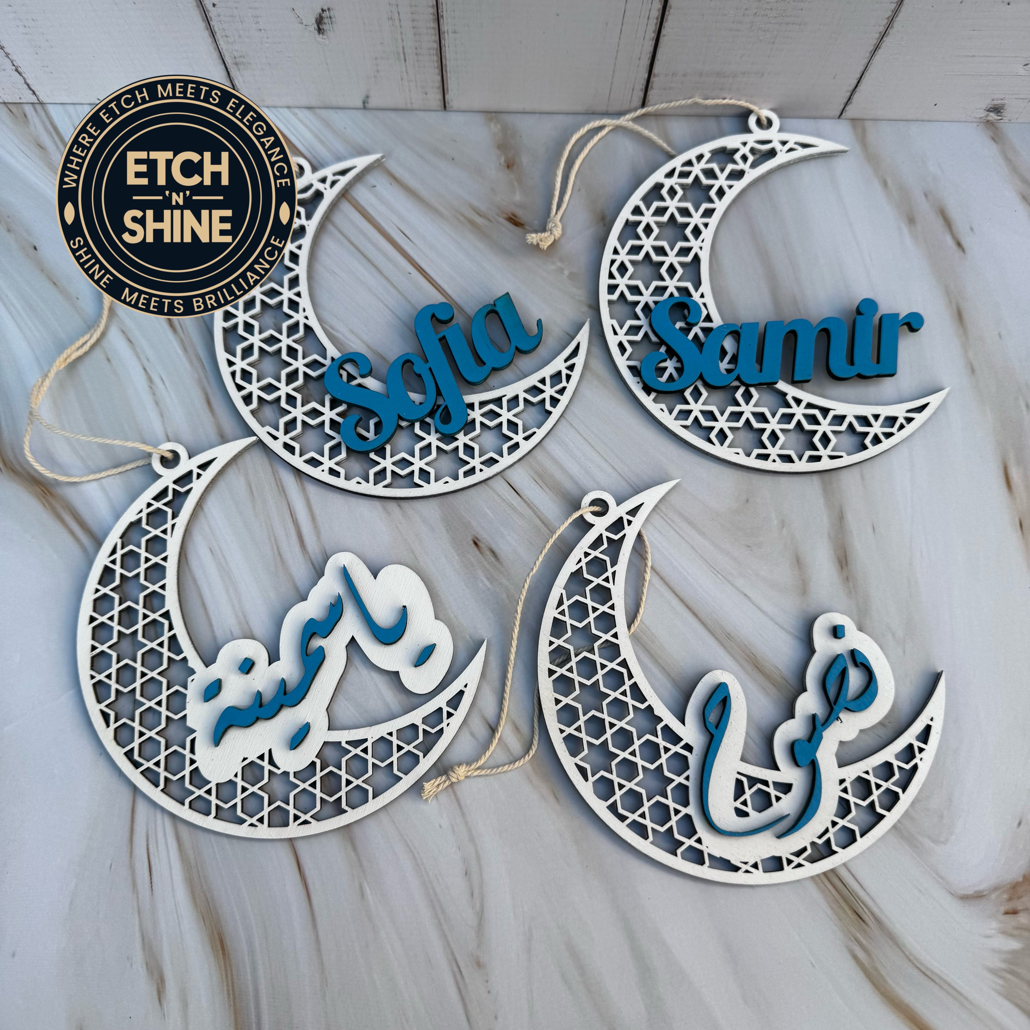 Decorative crescent moon ornaments with names 'Sofia' and 'Samir' on a wooden surface.