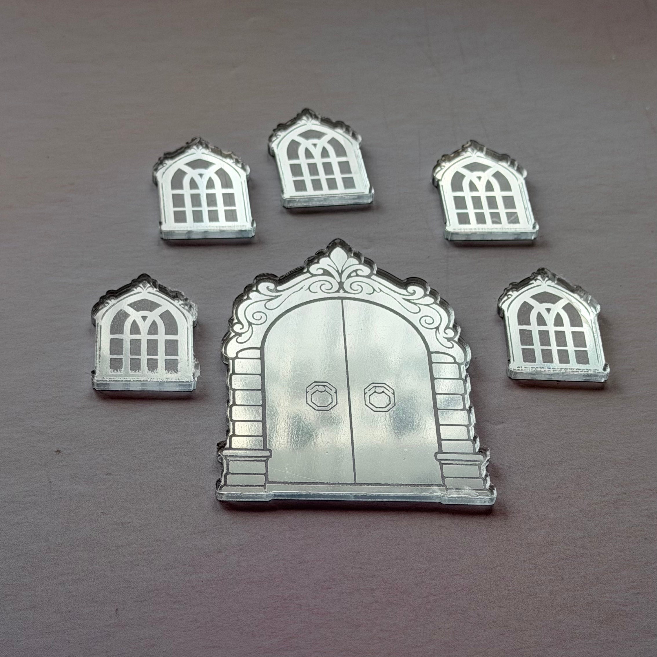 Set of decorative silver door and window shapes on a brown surface