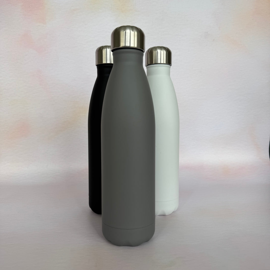 Three insulated bottles in black, gray, and white on a light background