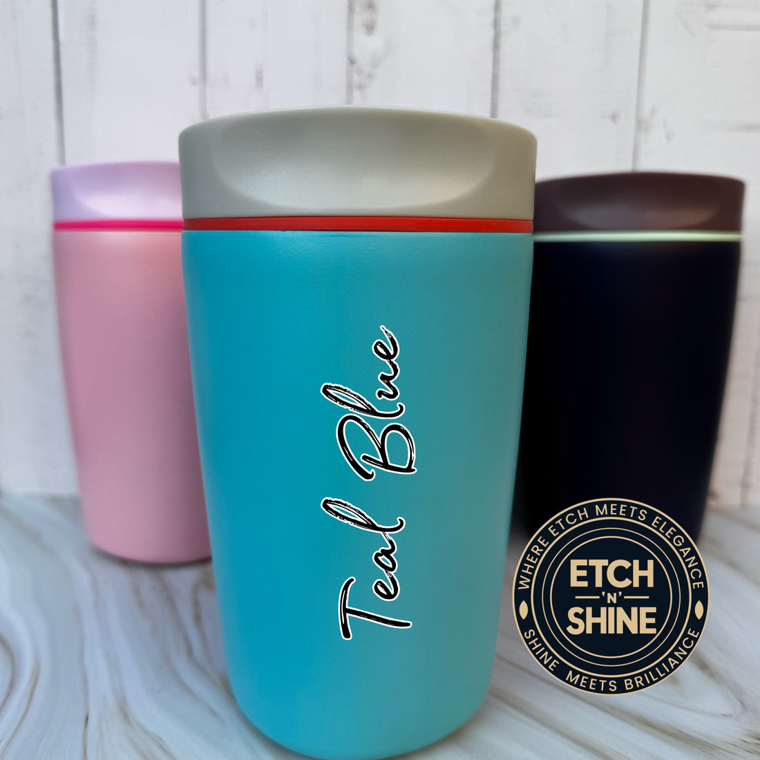 Teal blue tumbler with 'Teal Blue' text, pink and black tumblers in the background, Etch n Shine logo.
