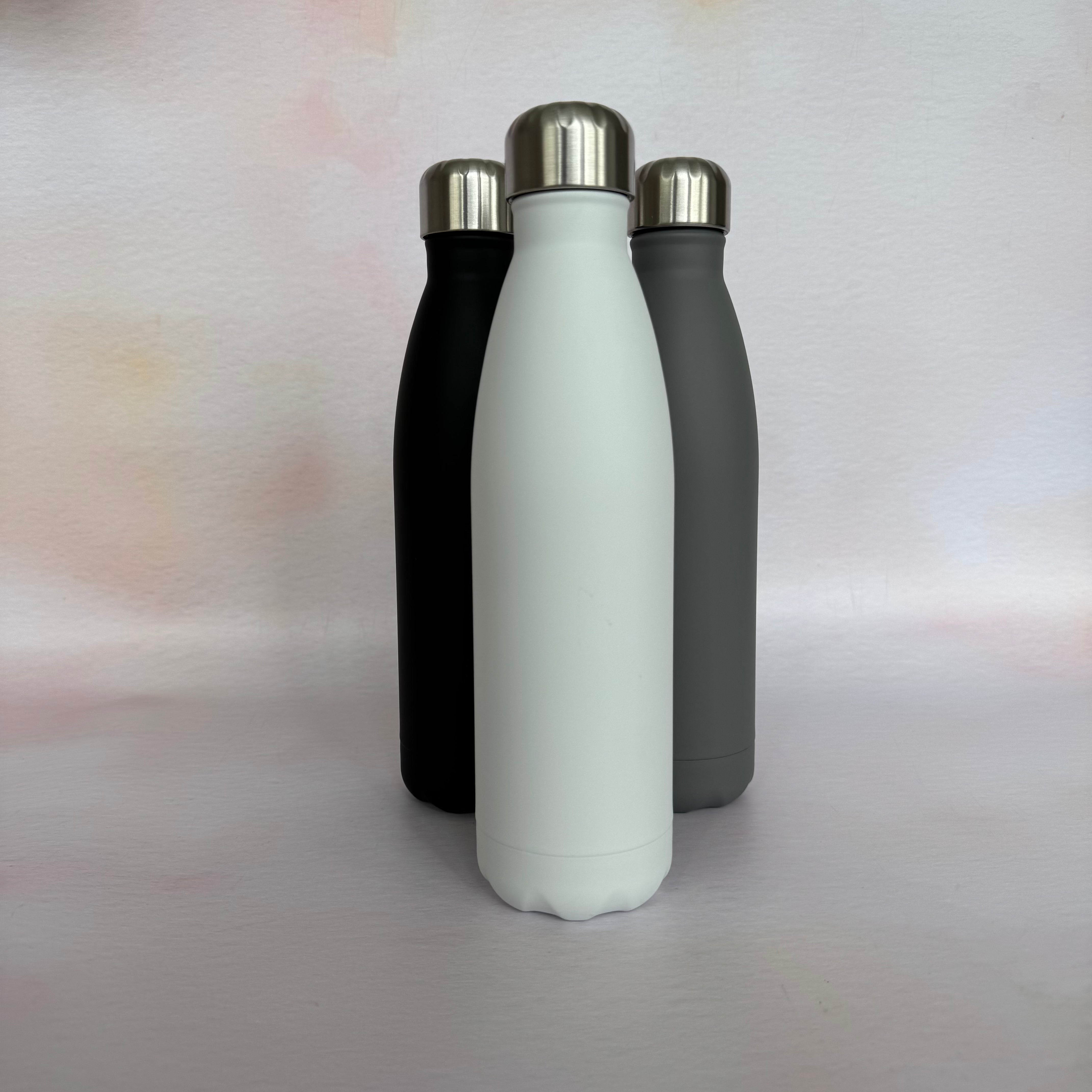 Three insulated bottles in black, white, and gray on a light background